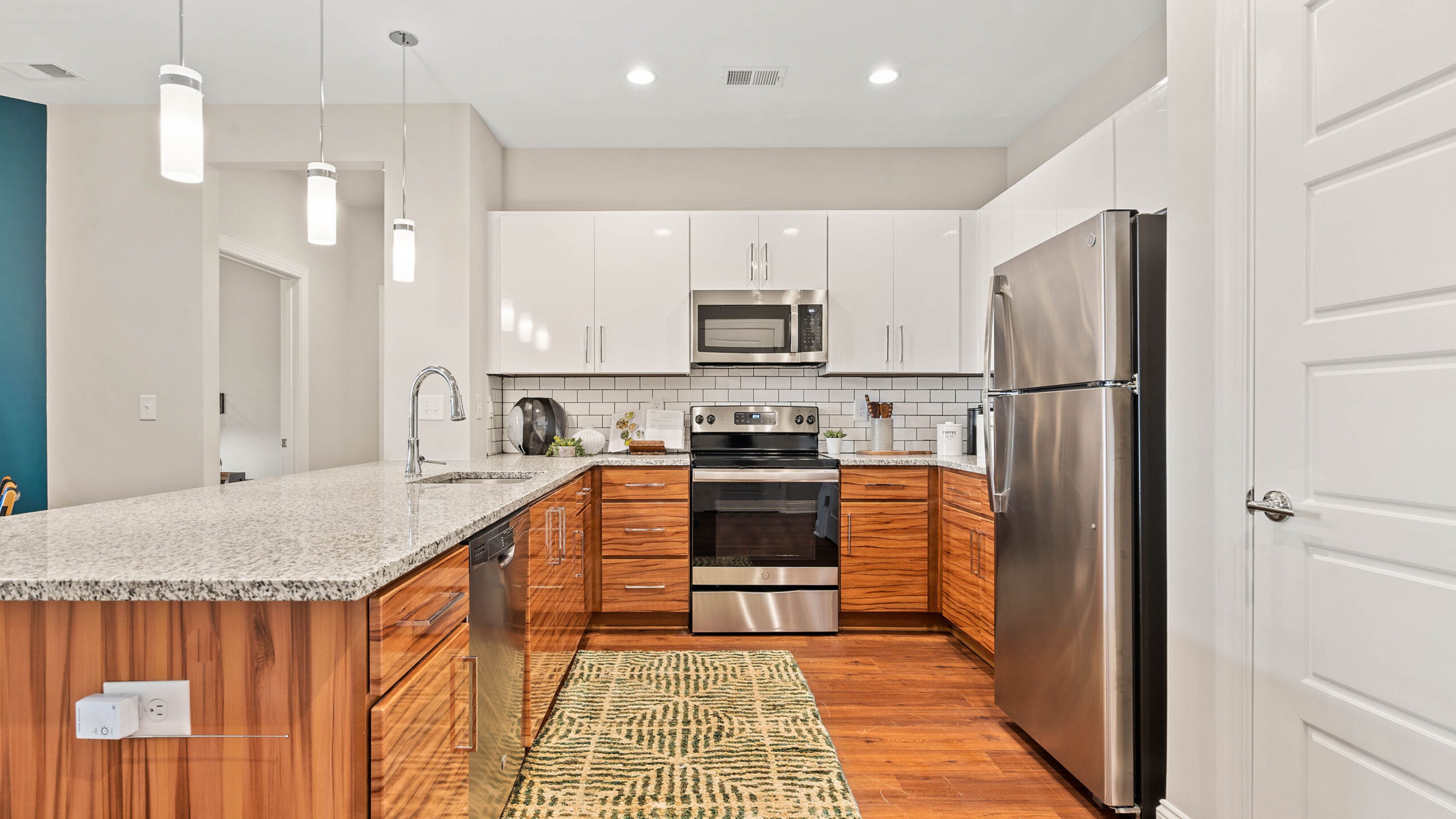 Hawthorne at Haywood apartment kitchen and living area with quartz countertops, stainless steel appliances, and ample cabinet storage